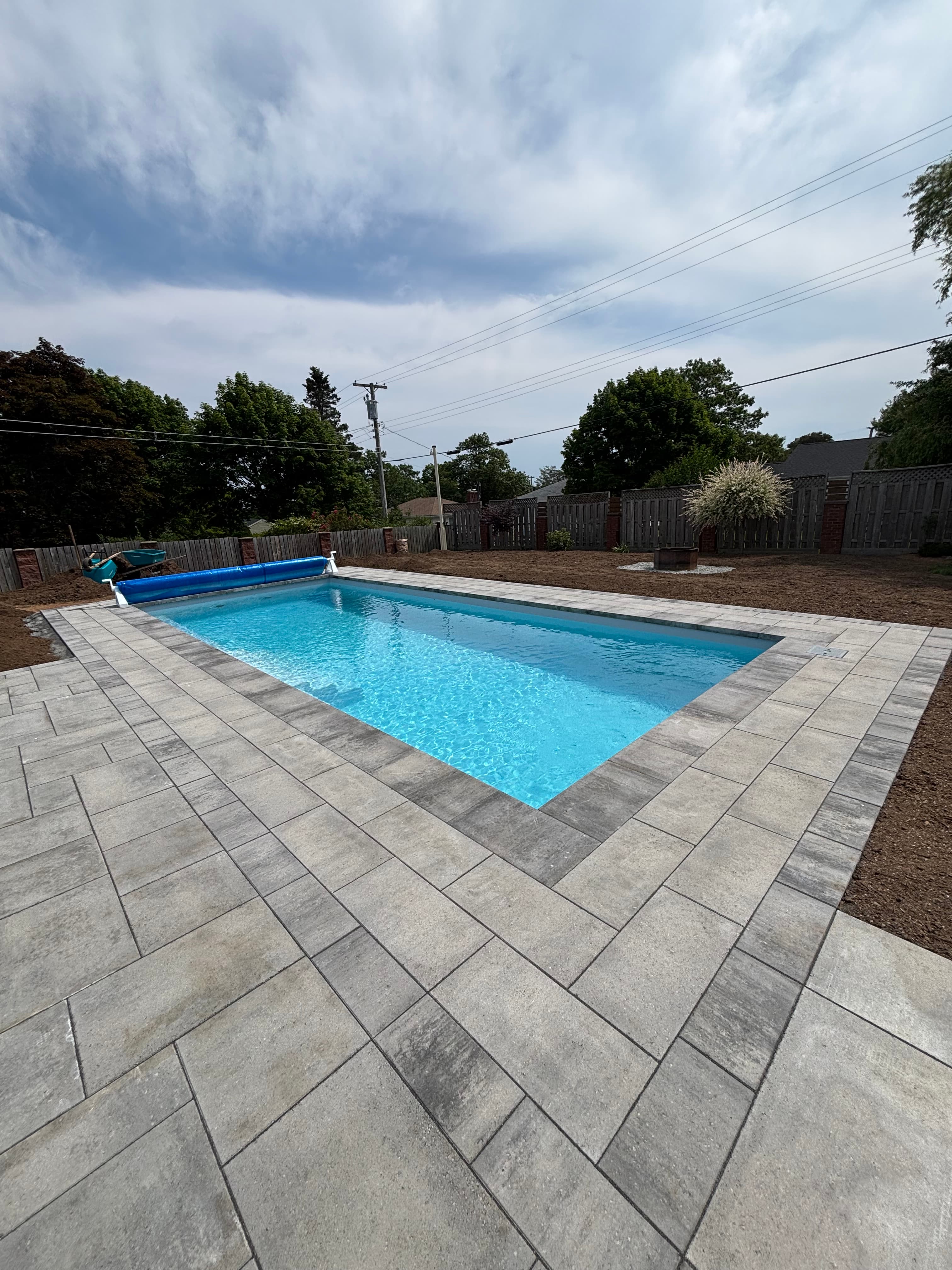 Fiberglass pool with cover roller and paver deck