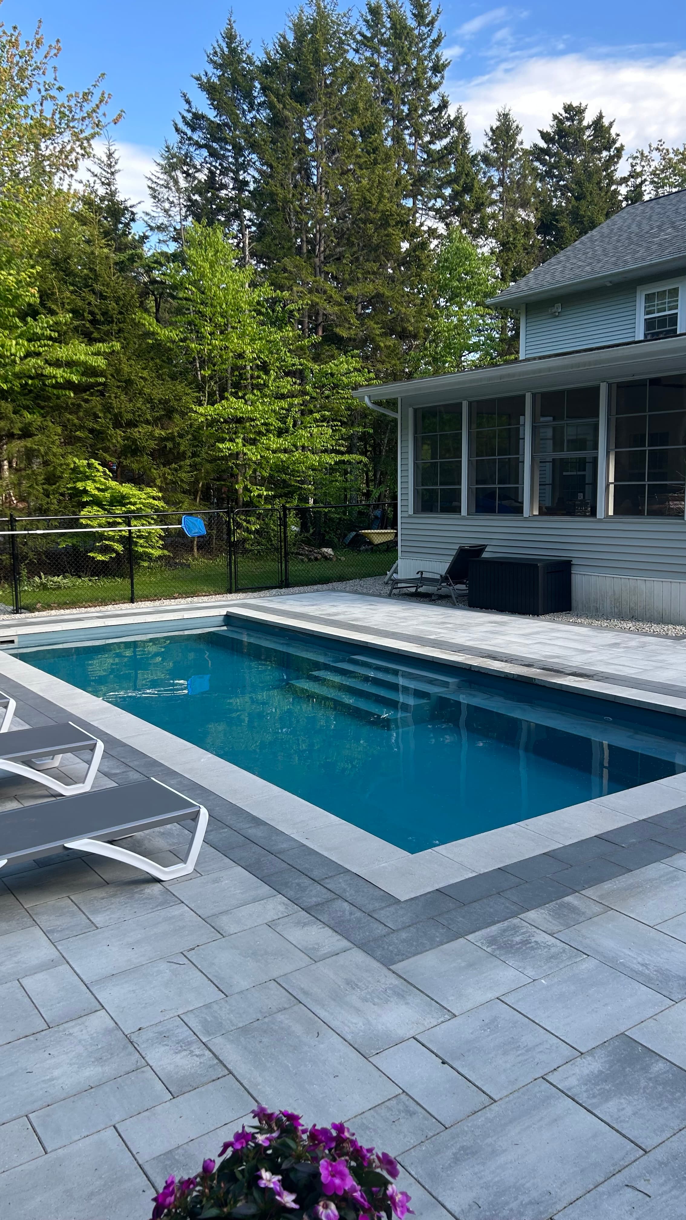 Fiberglass pool with grey paver patio and screened porch