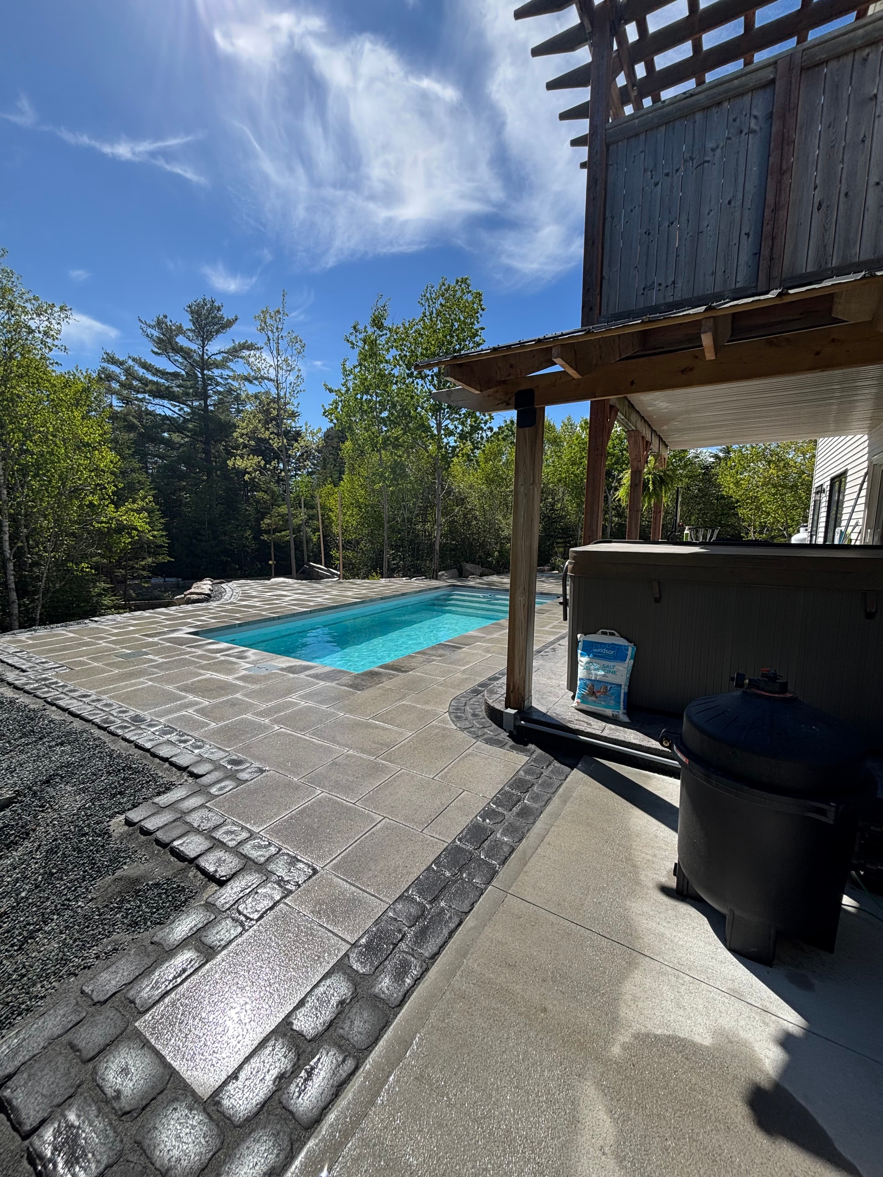 Plunge pool with cobblestone border and poolhouse hot tub