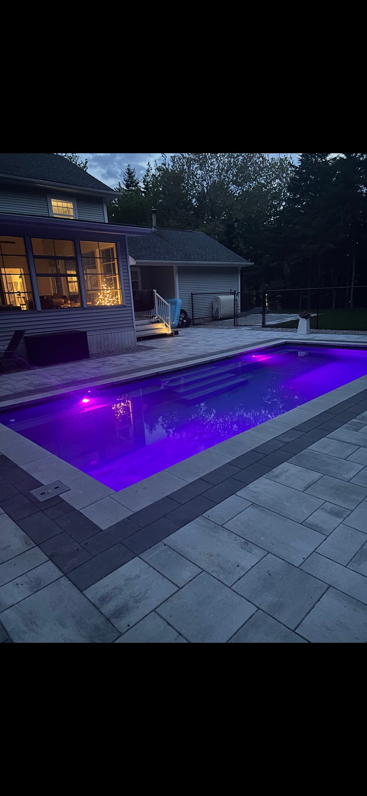 Fiberglass pool with purple LED lighting at twilight