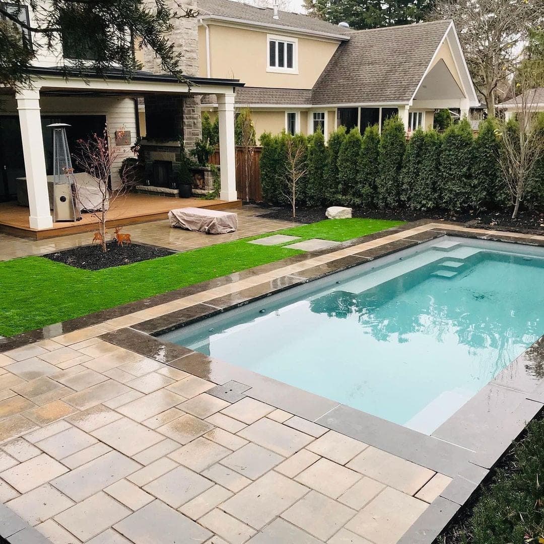 Grey fiberglass pool with paver surround