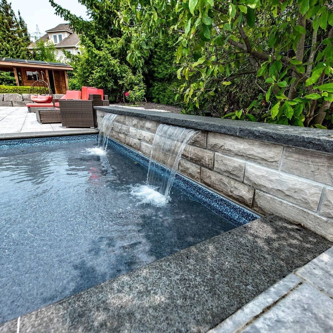 Pool with stone waterfall feature and outdoor lounge