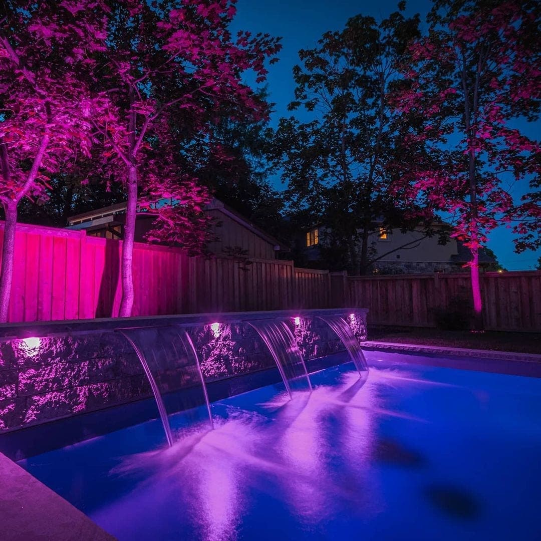 Pool with waterfall and dramatic purple feature lighting at night